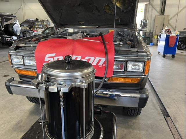 オイルチェンジャーを用いて、上抜きでオイル交換をしているランドクルーザー