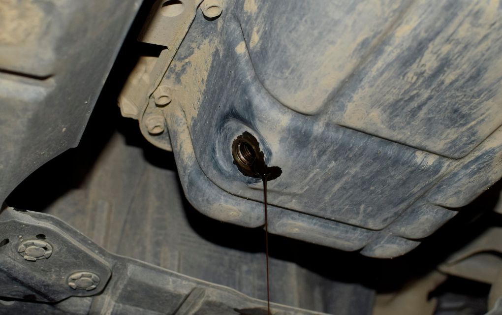 エンジンオイルの下抜きをしている様子。黒ずんだオイルが垂れている